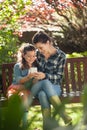 Smiling girl and mother using mobile phone while sitting on wooden bench Royalty Free Stock Photo