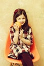 Smiling girl with orange in hand sitting in plastic chair Royalty Free Stock Photo