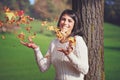 Smiling girl palying with autumn leaves