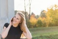 Smiling girl is phoning standing on the bridge and looking over herself