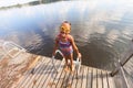 Smiling girl on the pier after swimming. Reflection of blue sky and white clouds in the water. Sunny summer day. Royalty Free Stock Photo