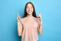 Smiling girl in pink T-shirt posing in studio and pointing up. Royalty Free Stock Photo