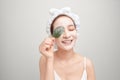 A smiling girl with a pink towel on her head applied a clay moisturizing mask while holding a leaf Royalty Free Stock Photo