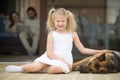 Smiling girl playing with dog outside house looking at camera Royalty Free Stock Photo