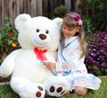 Smiling girl plays the doctor with huge toy white bear Royalty Free Stock Photo