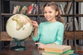 Smiling girl pointing at globe in library Royalty Free Stock Photo