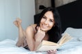 Smiling girl reading book on bed at home Royalty Free Stock Photo