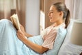 smiling girl reading book in bed at home Royalty Free Stock Photo