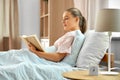 smiling girl reading book in bed at home Royalty Free Stock Photo