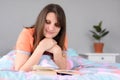 Smiling girl is reading a book and resting while lying in bed Royalty Free Stock Photo