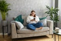 Smiling girl relaxing at home, she is listening to music, using a smartphone and wearing white headphones. Young 30s Royalty Free Stock Photo