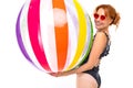 Smiling girl in retro one-piece swimsuit and sunglasses with a striped water ball on a white background