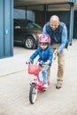 Smiling girl riding a bike with her father\'s hepl Royalty Free Stock Photo