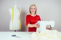 Smiling girl seamstress working on sewing machine and mannequin with yellow measuring tape on white background Royalty Free Stock Photo