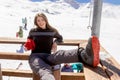 Smiling girl seated and rests after ski mountain view during ski vacation in Alps backgrounds. Outdoor in the mountains