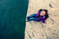 A smiling girl sits on the edge of a stone near the water. Royalty Free Stock Photo