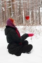 Smiling girl sits on snow and looks at hanging apple Royalty Free Stock Photo