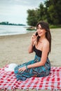 Smiling girl sitting at the beach and talking on the phone Royalty Free Stock Photo