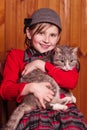 Smiling girl sitting on a chair and hugs beloved cat. On the farm.