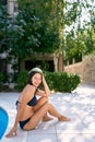 Smiling girl sitting on the edge of the pool with a watermelon on her head Royalty Free Stock Photo