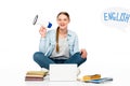 Smiling girl sitting on floor with loudspeaker near laptop, books and copybooks, English lettering in speech bubble