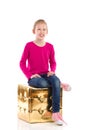 Smiling girl is sitting on a gold pouffe.