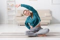 smiling girl sitting in lotus position on yoga mat and stretching