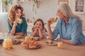 Smiling girl sitting between mother and grandmother at the kitchen table with food Royalty Free Stock Photo