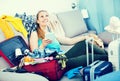 Smiling girl sitting on sofa and packing suitcase Royalty Free Stock Photo
