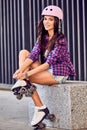 Smiling girl sitting the stairs and puts on roller skates Royalty Free Stock Photo