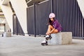 Smiling girl sitting the stairs and puts on roller skates Royalty Free Stock Photo