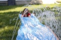 Smiling girl sliding down an outdoor slip and slide. selective focus on water in front of child Royalty Free Stock Photo