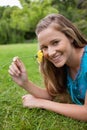 Smiling girl smelling a yellow flower while lying Royalty Free Stock Photo