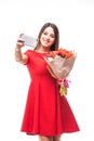 Smiling girl standing with a bouquet of colored tulips in their hands, make selfie phone on white Royalty Free Stock Photo