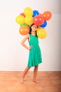Smiling girl standing with inflating balloons as hat