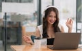 Smiling girl student wear wireless headphone study online with teacher, happy young asian woman learn language listen Royalty Free Stock Photo