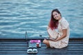 Smiling girl studying on pier near water. Laptop, notebook and cup of coffee. Distance learning and studentship concept Royalty Free Stock Photo