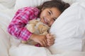 Smiling girl with stuffed toy resting in bed Royalty Free Stock Photo