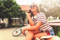 Smiling young woman sitting on a bench in the summer using smart phone Royalty Free Stock Photo