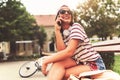 Smiling young woman sitting on a bench in the summer using smart phone Royalty Free Stock Photo