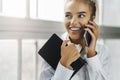 Smiling girl talking on smartphone, holding black notepad. Beautiful girl use mobile phone for work, call clients