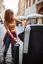 Smiling girl throwing garbage in recycling bin at city street