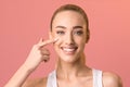 Smiling girl touching face applying facial cream posing in studio Royalty Free Stock Photo