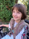 Smiling girl, in traditional Romanian costume, standing on the bench, representing cultural diversity