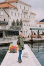 Smiling girl-traveler stands on the pier against the backdrop of the old house of Perast. Montenegro Royalty Free Stock Photo