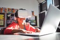 Smiling girl typing on laptop while using headphones and virtual reality glasses Royalty Free Stock Photo