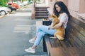 Smiling girl using smartphone hugging adorable shiba inu dog outdoors in cafe