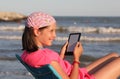 Smiling girl while using a tablet on the beach shore in summer w Royalty Free Stock Photo