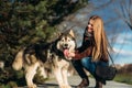 A smiling girl is walking with a dog along the embankment. Beautiful husky dog