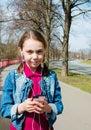 Smiling girl in warm sunny weather on the street with headphones listening to music in the gadget Royalty Free Stock Photo